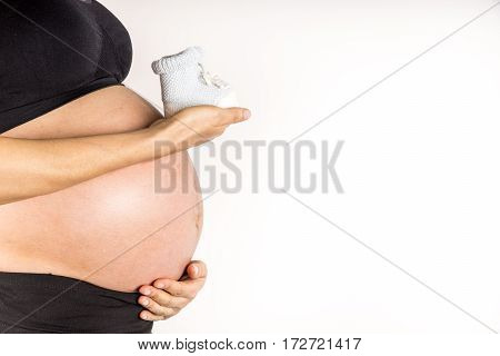 Mom holds blue little shoes on her belly