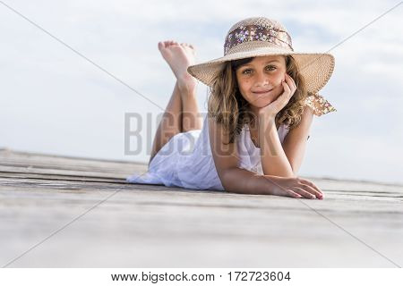 Girl with hat lying on the wooden walkway