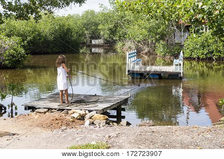 Girl stretching from the barge to cross the creek.