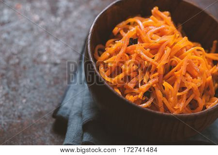 Asian korean carrot salad with spices and garlic in the wooden bowl horizontal