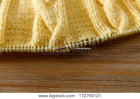 Yellow Knitted Work in ProcessGrey Knitting Needles.Hand Made;Fancywork.Wooden Background