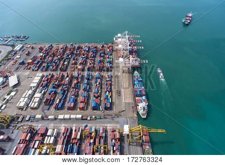 container ship in import export and business logistic. By crane Trade Port Shipping. Tugboat assisting cargo to harbor. Aerial view.
