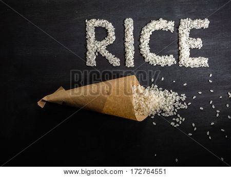 White Rice Scattered Over The Dark Wooden Table Of A Paper Bag.