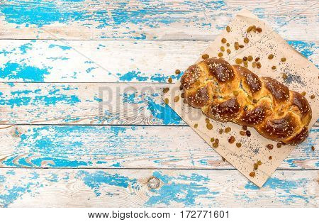 Fresh bun with raisins and poppy seeds on wooden background.