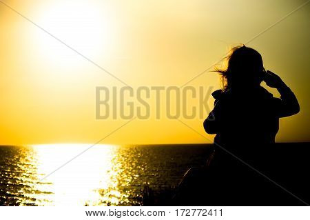 The child on sea background with the setting sun on the horizon