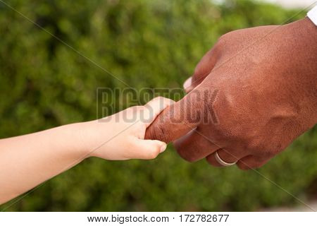 Multicultural family. Father and son holding hands.