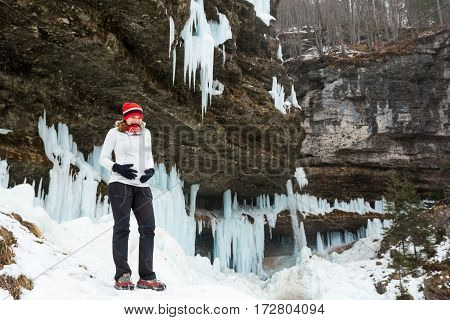 Young pregnant woman smiling on winter landscape. Icicles and snow in the background.