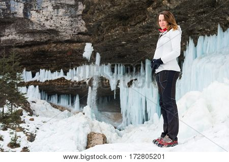 Young pregnant woman smiling on winter landscape. Icicles and snow in the background.