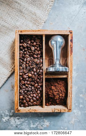 Freshly ground coffee coffee beans and tamper in vintage wooden box