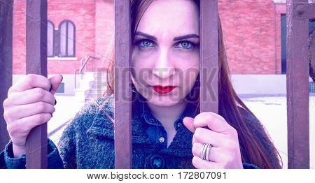 Sad woman behind bars staring intently into the eyes of camera with depressed facial expression hopeless - Concept of people mental heath and today social human problems