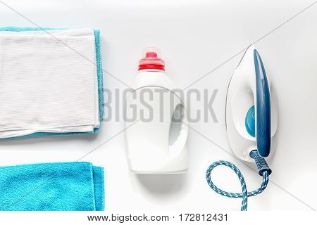 laundry set with bright towels and plastic bottels of detergent on white table background top view