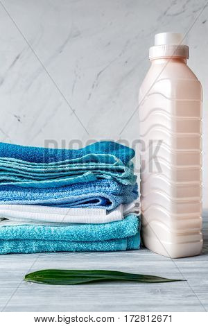 laundry set with bright towels and plastic bottels of detergent on gray table background mock up