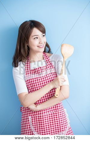 beauty housewife take rice spoon and look somewhere isolated on blue background