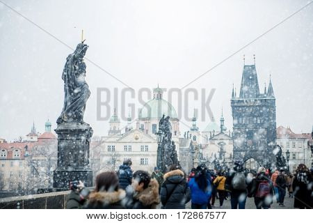 Tourists visiting Charles Bridge (Karlùv Most) in Prague under the snow.