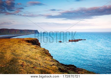 Great view on Kirkjufjara beach and sunny hills. Popular tourist attraction. Picturesque and gorgeous scene. Location place Sudurland, cape Dyrholaey, Vic village, South Iceland, Europe. Beauty world.
