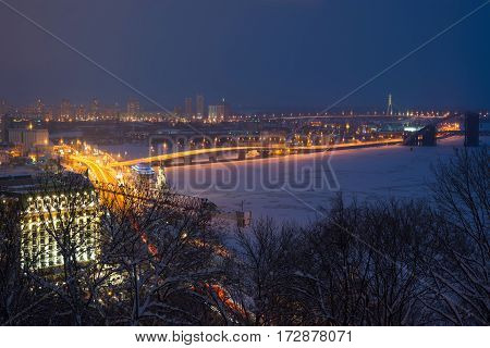 Podol region of Kiev and frosted Dnieper river evening view with illumination. Little Saint Nicolas church on the water also is seen on image.