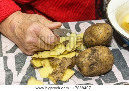 Close-up of hands peeling potato before cooking