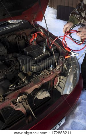 Mechanic jumper cables connected to a discharged battery.
Firing the car in the winter by the jumper cables.