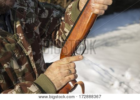 Hunter dressed in camouflage with pneumatic gun, rifle Man's hands holding a flask with a long gun hunting.