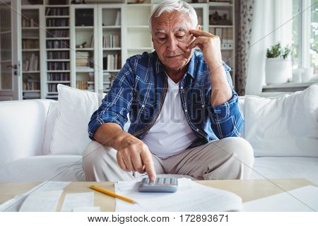 Tensed senior man checking the bills at home
