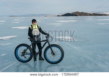 Fatbike also called fat bike or fat-tire bike - Cycling on large tire wheels. Cyclist goes to his bike on the frozen lake.