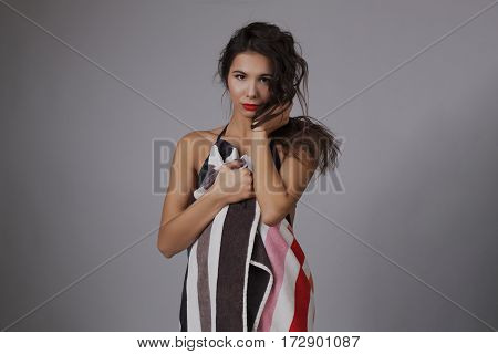 Fashion photo of beautiful and young lady in swimsuits posing in studio, holding colorful towel