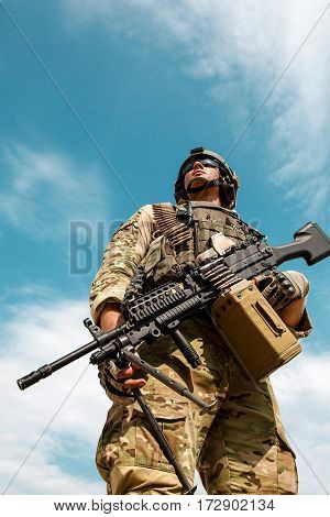 Low angle portrait of US Army Ranger with machinegun on blue sky background looking up. National pride concept