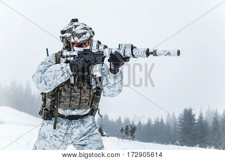 Winter arctic mountains warfare. Action in cold conditions. Trooper with weapons in forest somewhere above the Arctic Circle