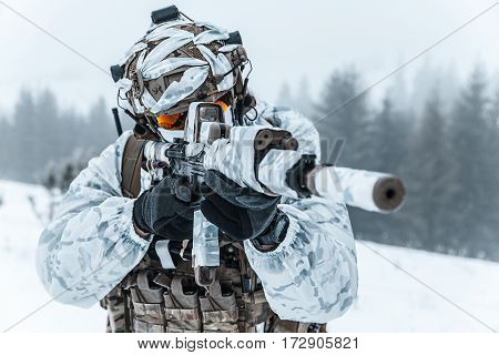 Winter arctic mountains warfare. Action in cold conditions. Trooper with weapons in forest somewhere above the Arctic Circle