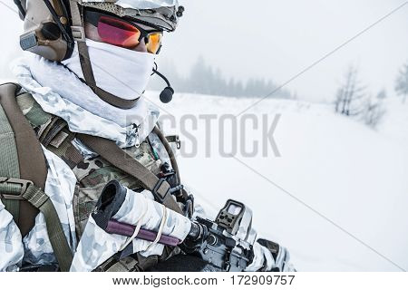 Winter arctic mountains warfare. Action in cold conditions. Trooper with weapons in forest somewhere above the Arctic Circle