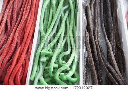 Various multi colored confectionery in the candy shop. Colorful tasty licorice candies for sale on retail market candy shop