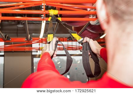 white curly bearded sporty man exercising with fitness straps in gym