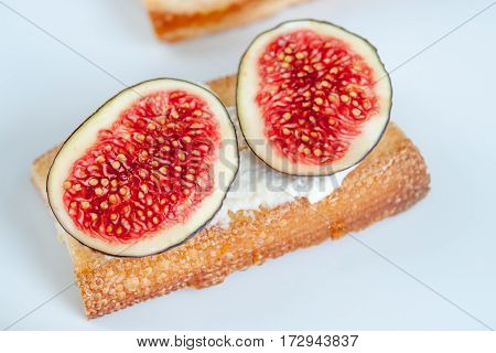 Bruschetta with fresh figs and chease on white plate