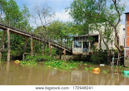 A weathered bridge and buildings within the Meking River delta in South vietnam in near the town of Vinh Long.