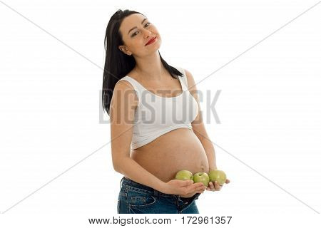 pregnant cheerful brunette woman with big belly and green apples in her hands posing on camera isolated on white