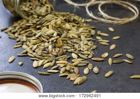 Dried sunflower seeds spilling out of a glass jar.