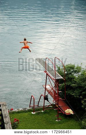 HALLSTADT, AUSTRIA, JULY 07, 2006: Courageous boy jumps from a diving board into the lake