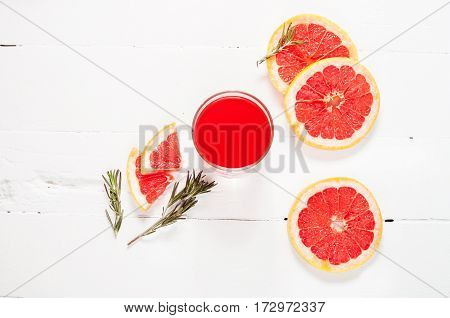 Grapefruit juice and ripe grapefruits on a wooden background.