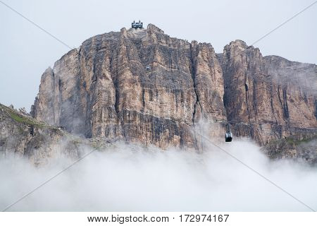 Sass Pordoi mountain massif hidden in clouds with cable car leading on top Dolomites Italy