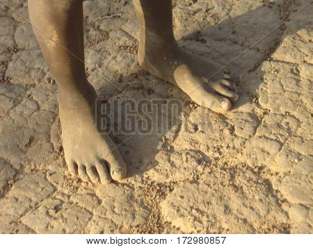 Person standing on drought-affected cracked soil in Burkina Faso, West Africa