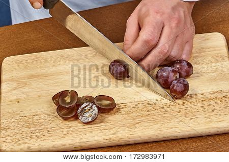 Chef-cook sliced grapes on a cutting board. Cutting ingredients closeup
