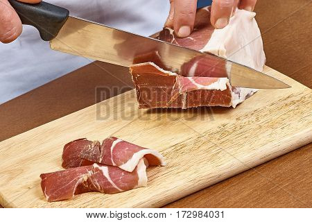 Dry cured ham thinly sliced Closeup on chef hands slices prosciutto Italian delicatessen dishes cooking process