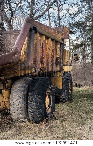 Rusting and overgrown heavy yellow industrial truck and equipment abandoned in economic recession