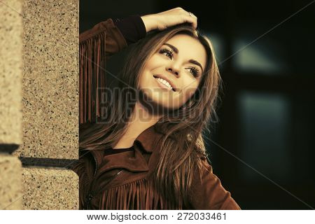 Happy young fashion woman walking on city street Stylish female model wearing leather fringe suede jacket 