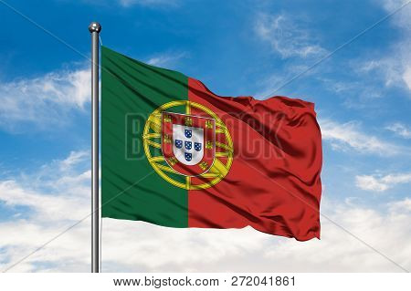 Flag Of Portugal Waving In The Wind Against White Cloudy Blue Sky. Portuguese Flag.