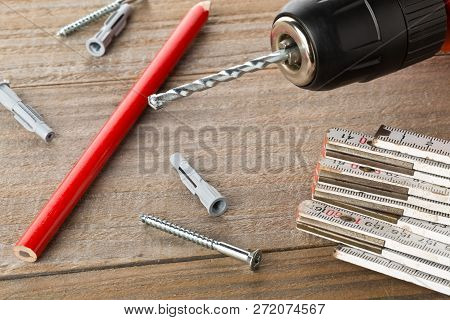 Wall Plug Dowel With Screw, Electric Power Drill, Folding Rule And Pencil On Wooden Table - Home Imp