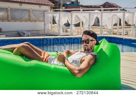 Young Man Enjoying Leisure, Lying On The Air Sofa Lamzac, Near The Pool