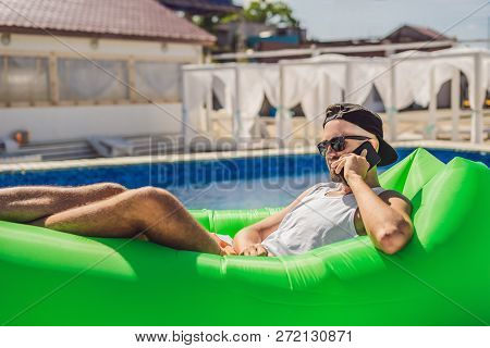 Young Man Enjoying Leisure, Lying On The Air Sofa Lamzac, Near The Pool