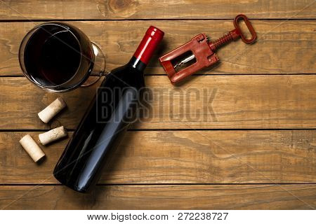 Bottle Of Wine Glass Corkscrew And Corkscrew On Wooden Background. Top View With Copy Space.