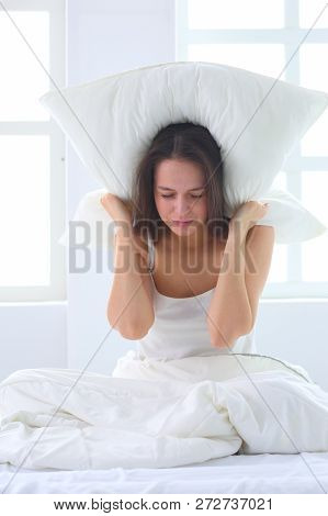 Young Caucasian Woman Covering Her Head And Ears With Pillows